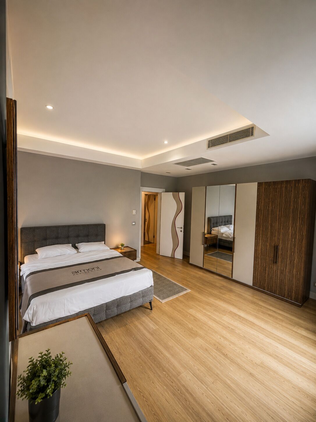 Un dormitorio moderno con una cama grande, un armario y un espejo.