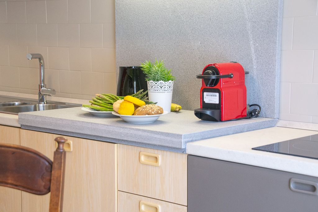 Un plan de travail de cuisine avec une machine à café, une plante en pot et des légumes frais.
