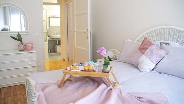 Quarto bem arrumado com uma cama, mesa de cabeceira e bandeja com itens de café da manhã.