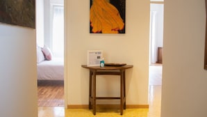 Quarto de hotel com uma cama, uma mesa de cabeceira com abajur e um quadro na parede.