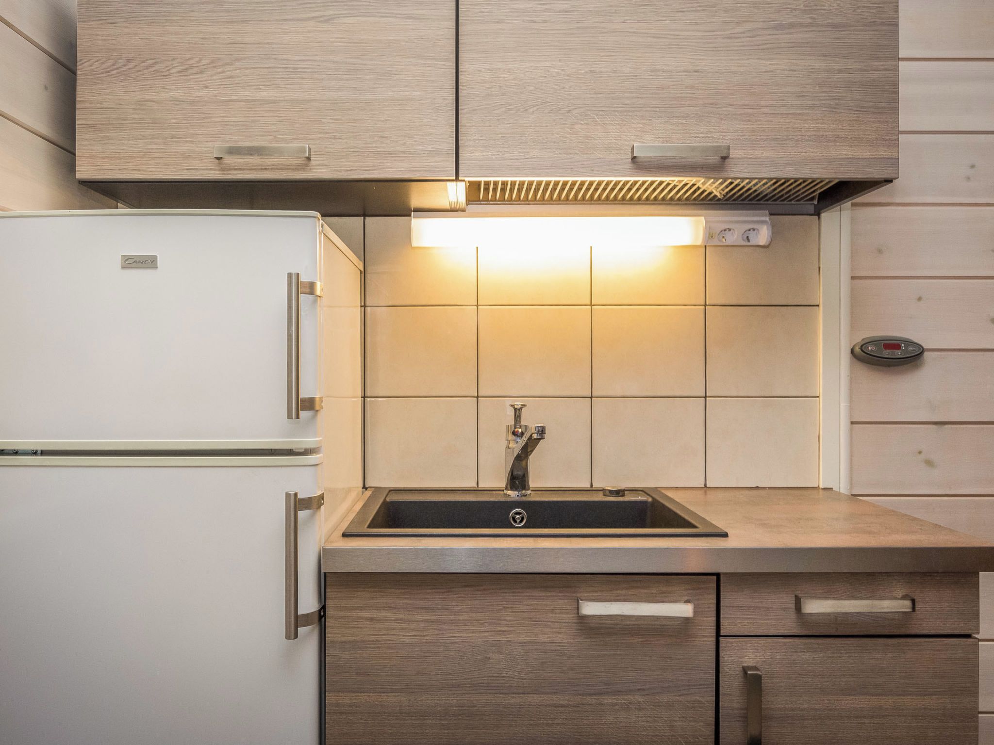 Una cocina con un refrigerador blanco, un lavamanos con grifo y armarios de madera.