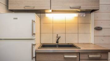 Una cocina con un refrigerador blanco, un lavamanos con grifo y armarios de madera.