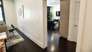 Una sala de estar moderna con comedor, una planta grande y un televisor de pantalla plana montado en la pared.