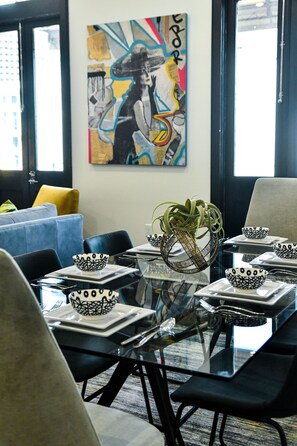 A modern dining area with a glass table, black chairs, and white plates with black patterns. - Vibrant Downtown New Orleans Escape: Prime CBD Location + Walk Everywhere (New Orleans)