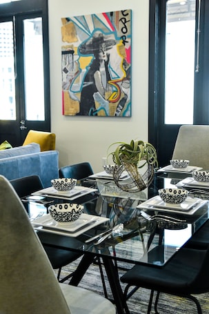 A modern dining area with a glass table, black chairs, and white plates with black patterns.