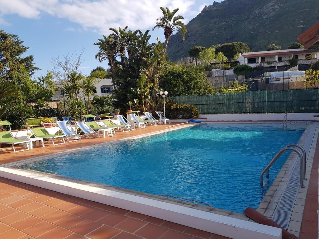 A swimming pool with lounge chairs and a mountain backdrop.