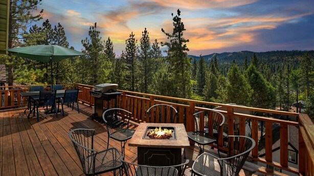 A wooden deck with outdoor furniture, a fire pit, and a view of a forested landscape. - View Point - Hot Tub, Pool Table, Arcade Game, Slope Views (Big Bear Lake)