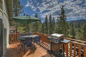 Une terrasse en bois avec une table et des chaises, un barbecue et un parasol.