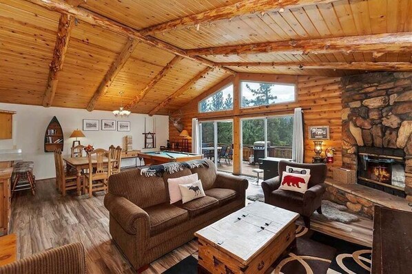 A cozy cabin interior with a wooden ceiling, a stone fireplace, a pool table, and a dining area. - View Point - Hot Tub, Pool Table, Arcade Game, Slope Views (Big Bear Lake)