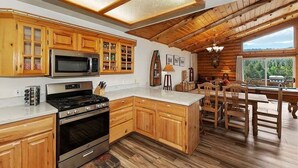 A kitchen with wooden cabinets, a stove, and a microwave. - View Point - Hot Tub, Pool Table, Arcade Game, Slope Views (Big Bear Lake)