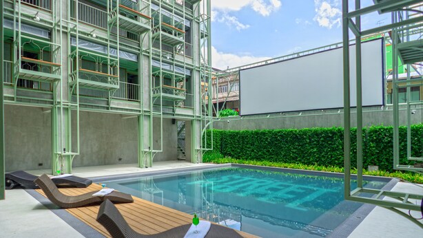 A swimming pool area with lounge chairs and a large white screen.