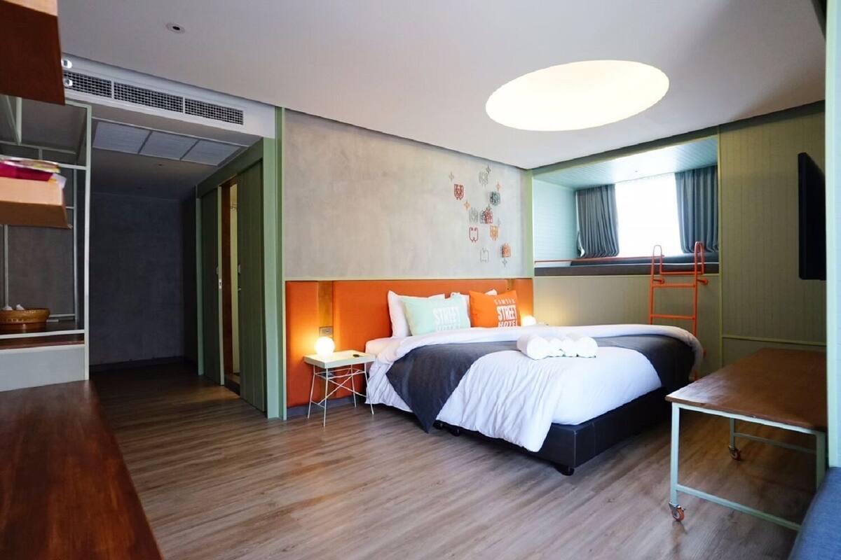Een hotelkamer met een bed, nachtkastje en een tafeltje met een lamp.