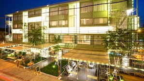 A modern hotel with multiple floors, outdoor seating areas, and a covered patio.