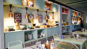 A restaurant with a long counter, green cabinets, and copper pendant lights.