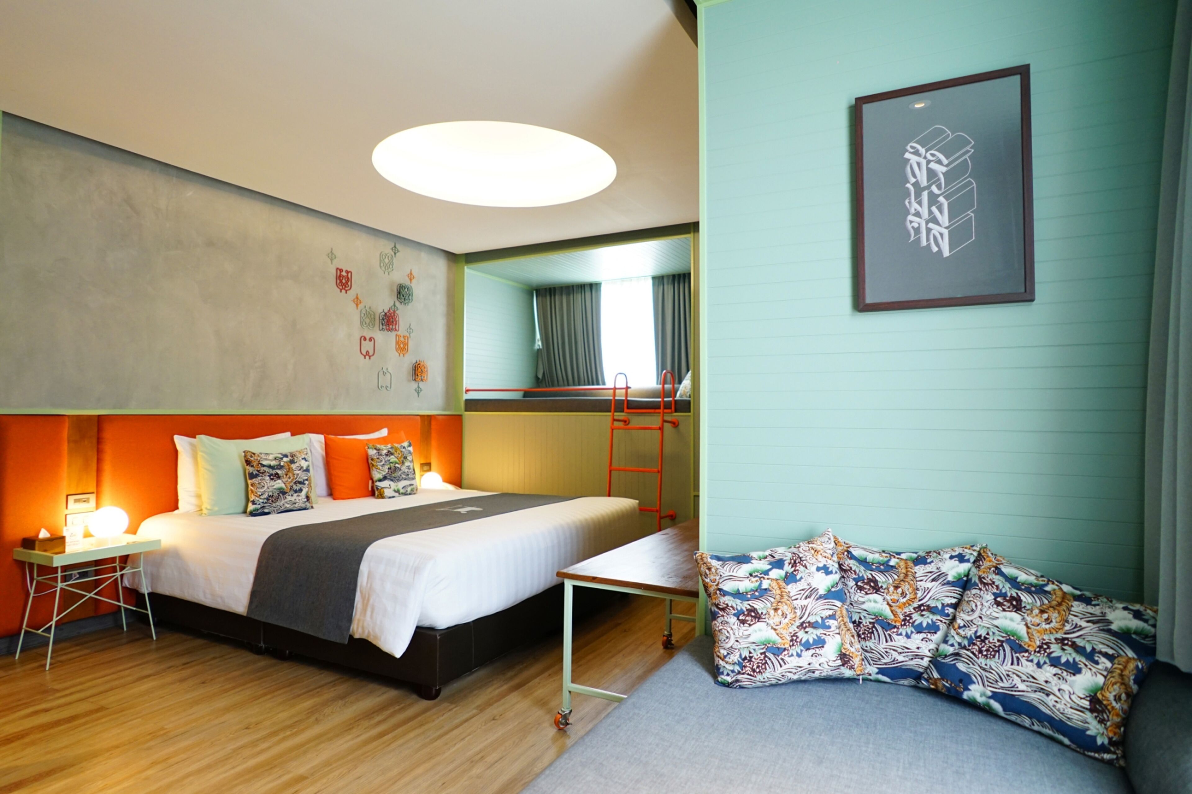 A hotel room with a bed, a desk, a chair, a bunk bed, and a sofa.