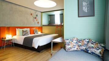 A hotel room with a bed, a desk, a chair, a bunk bed, and a sofa.