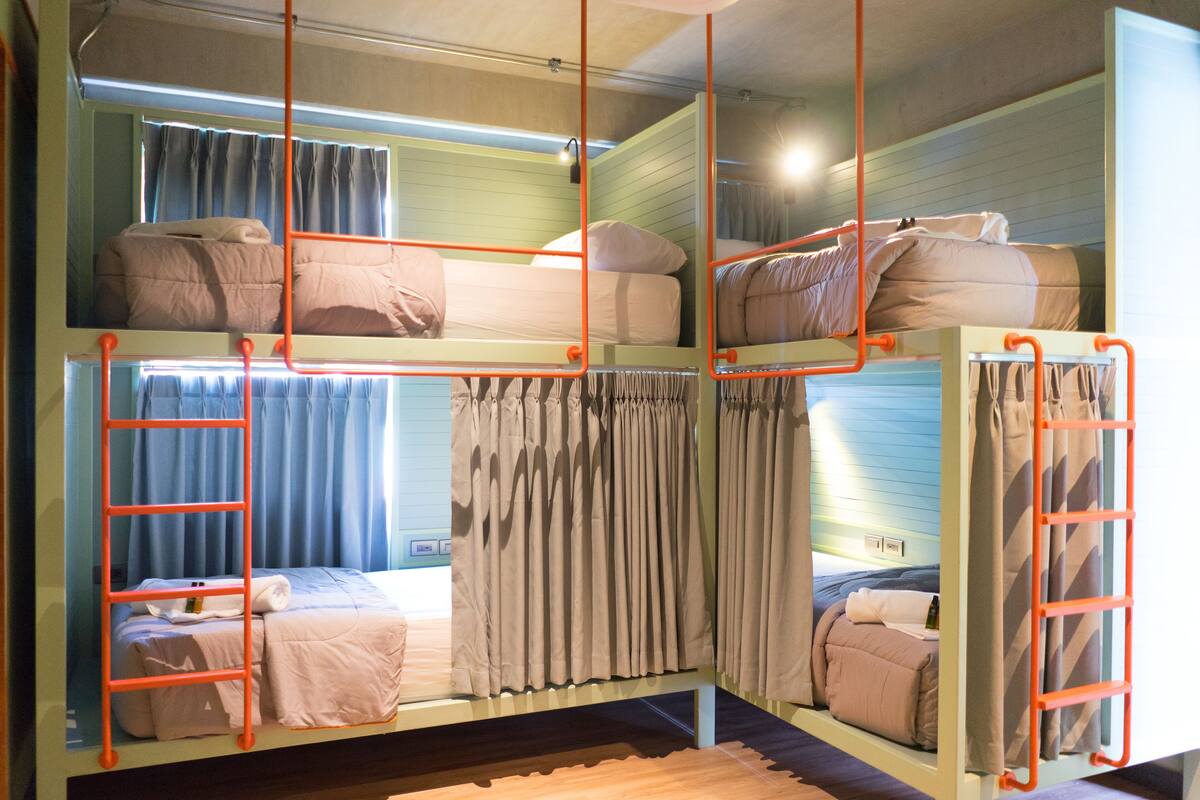 Een slaapkamer met stapelbedden, elk met een ladder, en gordijnen.