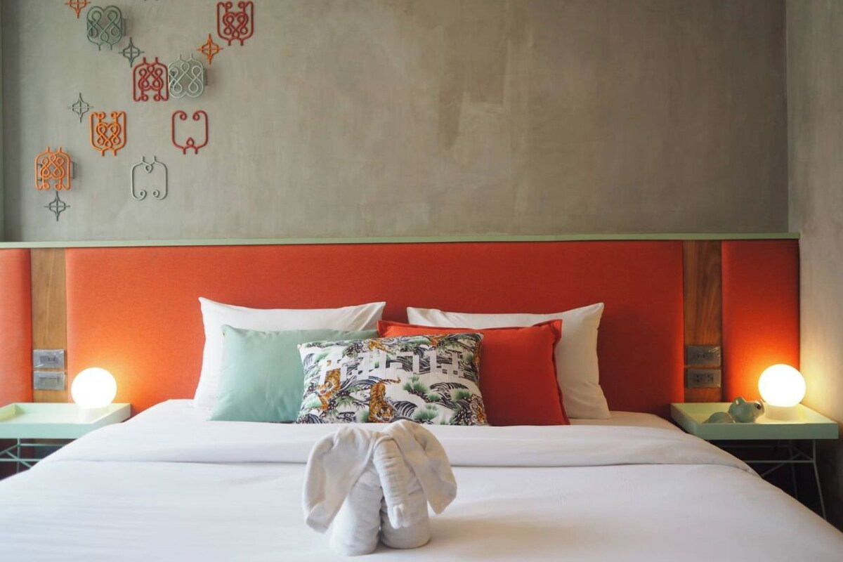 Habitación de hotel con cama, almohadas, una obra de arte en la pared y lámparas de noche.