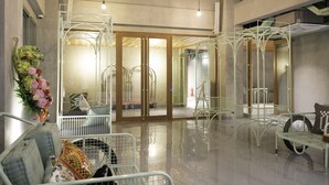 A spacious lobby with a polished floor, metal furniture, and a large mirror reflecting the interior.