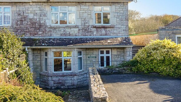 A stone house with a pitched roof and multiple windows.
