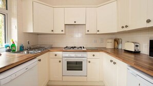 A kitchen with white cabinets, a wooden countertop, a stove, a toaster, and a bread container.