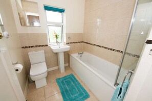Une salle de bain avec des toilettes, un lavabo et une baignoire.