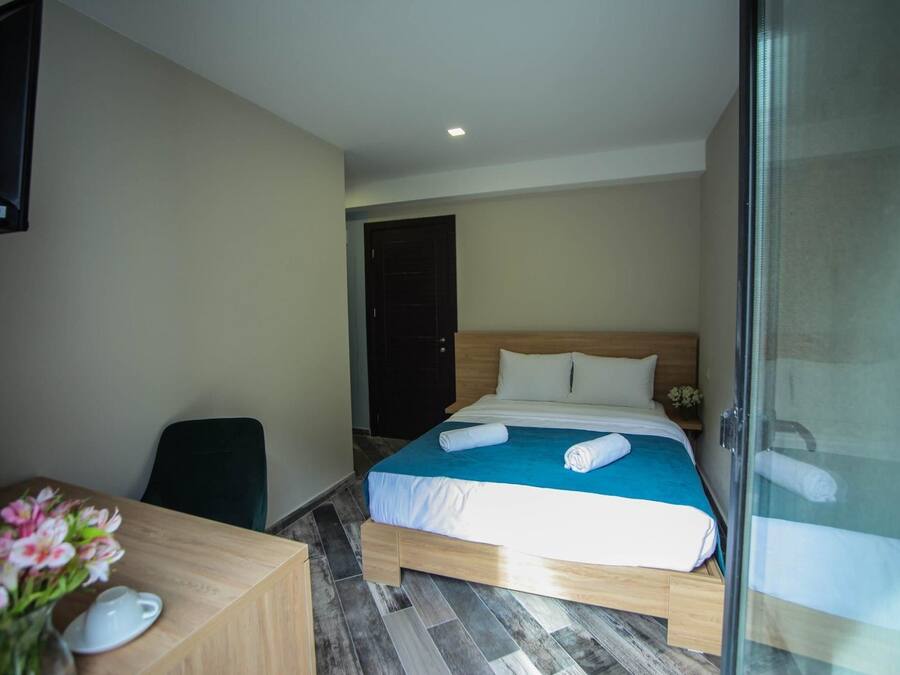 A hotel room with a bed, a desk, and a chair.