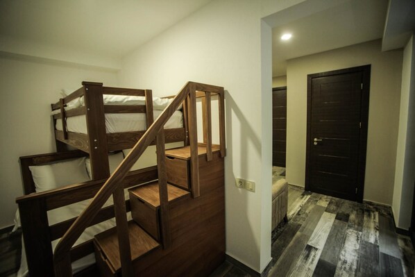 A room with a wooden bunk bed and a staircase.