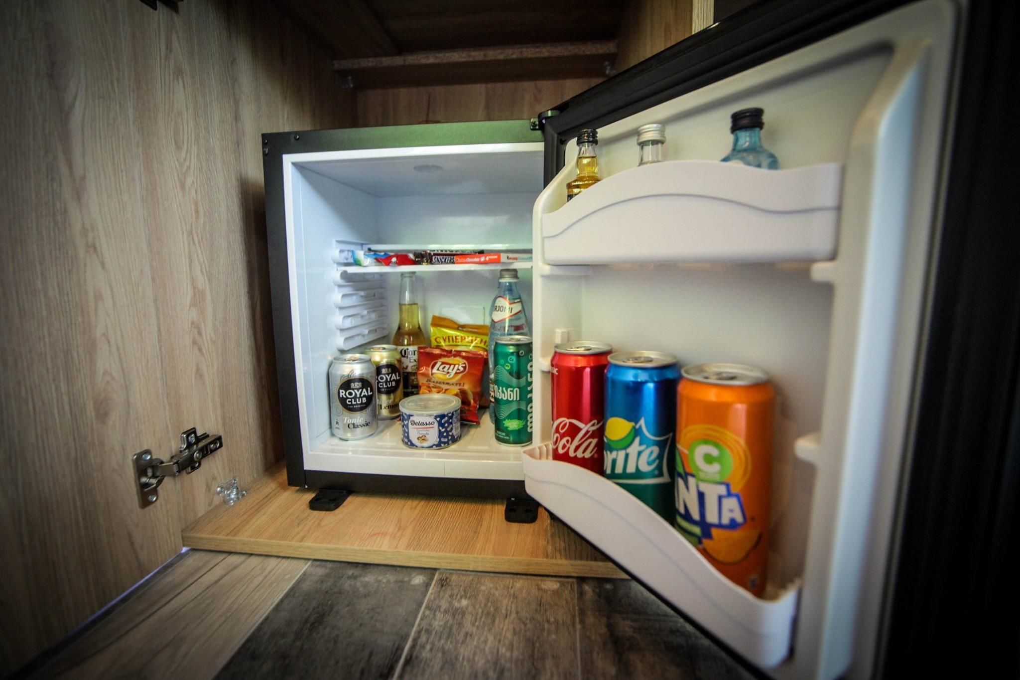 A compact refrigerator with shelves containing various beverages and snacks.