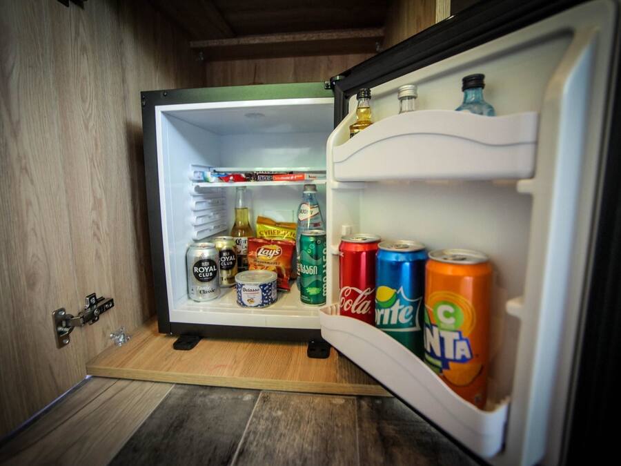 A compact refrigerator with shelves containing various beverages and snacks.