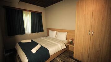 Una habitación de hotel con una cama de madera, una mesita de noche con un jarrón de flores y un armario.
