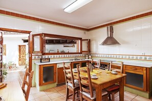 Une cuisine dotée d’un îlot central, de chaises en bois, d’une table à manger et d’une grande fenêtre.