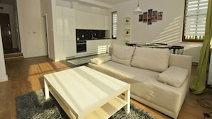 Een moderne woonkamer met een bank, een salontafel en een keuken in de achtergrond.