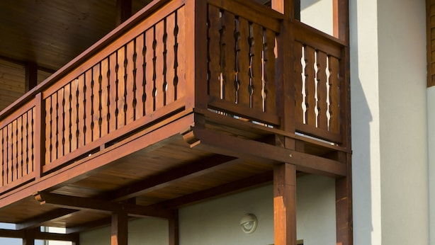 Een gebouw met twee verdiepingen, een balkon, stenen trappen en een rij potplanten.