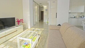 Een moderne woonkamer met een flatscreen televisie, een glazen salontafel en een beige bank.