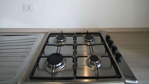 Une cuisine moderne dotée d’une hotte en acier inoxydable, d’une cuisinière à gaz avec quatre brûleurs et d’un plan de travail en bois.