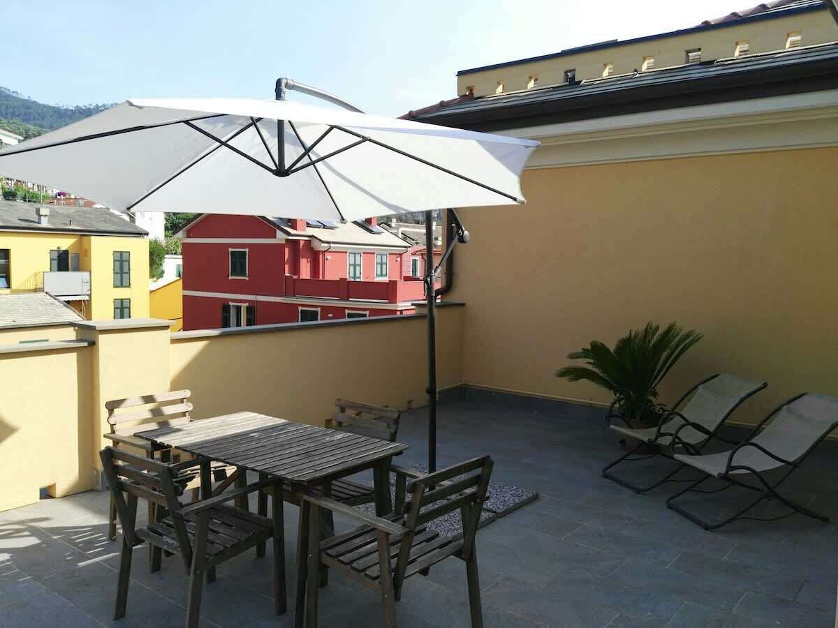 Ein Balkon mit Tisch, Stühlen, einem weißen Sonnenschirm und einem Blumentopf.