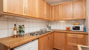 A kitchen with wooden cabinets, a dishwasher, a microwave, and a sink. - Regina's Banyuls - Apartment with the best view over Banyuls and the sea (Banyuls-sur-Mer)