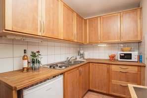 A kitchen with wooden cabinets, a dishwasher, a microwave, and a sink.