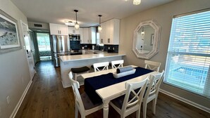 A modern kitchen with stainless steel appliances, a dining area with a table and chairs, and a large mirror on the wall. - Stay right on the beach.  Enjoy the view from our updated home right on the Gulf (Gulf Shores)