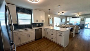 A modern kitchen with white cabinets, a built-in dishwasher, and a large island with a sink. - Stay right on the beach.  Enjoy the view from our updated home right on the Gulf (Gulf Shores)