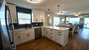 A modern kitchen with white cabinets, a built-in dishwasher, and a large island with a sink.