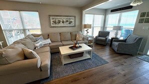 Un salon avec un canapé beige, une table basse blanche et un fauteuil gris.