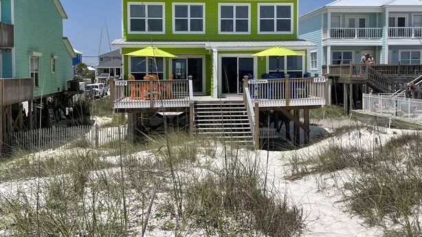 A two-story beach house with a covered deck and outdoor seating. - Stay right on the beach.  Enjoy the view from our updated home right on the Gulf (Gulf Shores)