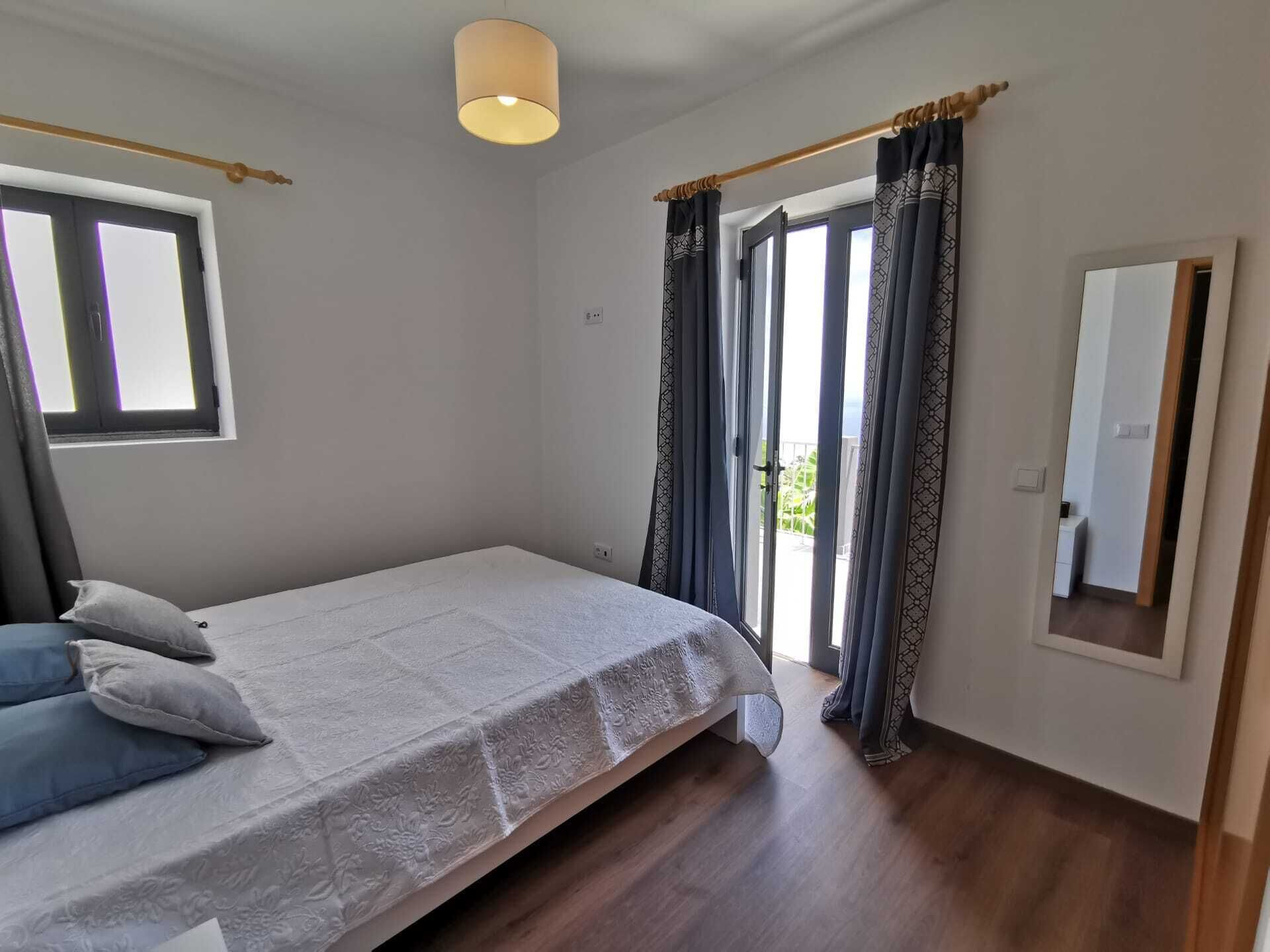 Un dormitorio con cama, cortinas, una ventana y una puerta que da a un balcón.