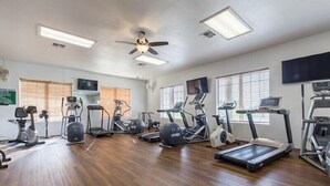 A gym with various exercise equipment, including treadmills, stationary bikes, and elliptical machines.