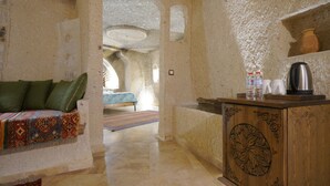 A room with a sofa, a wooden cabinet, and a bed with a patterned bedspread. - Kaya Konak Cave Hotel (Nevsehir)