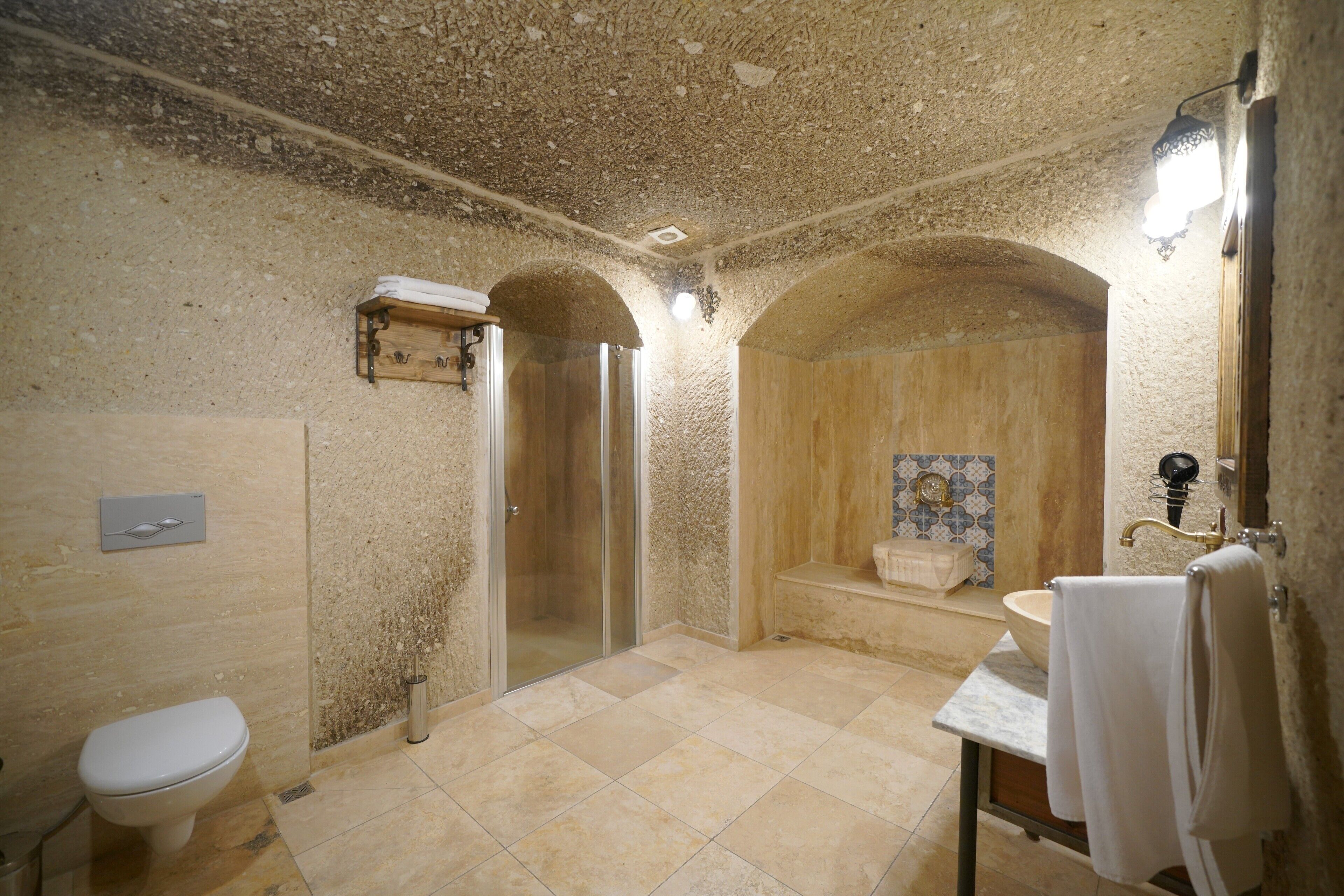 A bathroom with a toilet, shower, sink, and a towel rack.