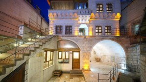 A historic building with a courtyard, stone archways, and a staircase leading to the upper floors. - Kaya Konak Cave Hotel (Nevsehir)
