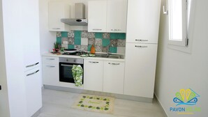 Eine moderne Küche mit weißen Schränken, einer Edelstahl-Spüle und einer gefliesten Spritzschutzwand.